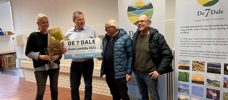 Foto af to repræsentanter fra foreningen De 7 Dale, som modtager check og blomster.
