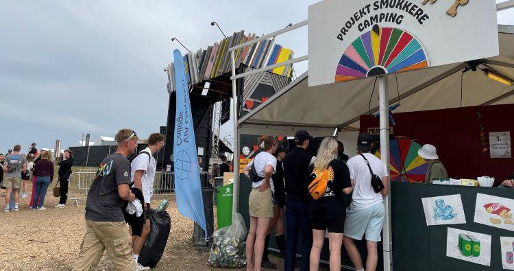 Festivalgæster afleverer sække med affald ved stand.
