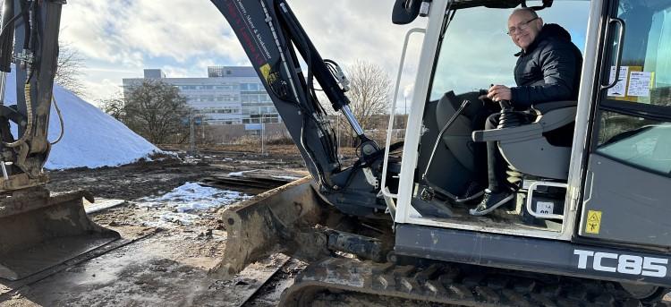 Foto af byggepladsen med udvalgsformand Tage Nielsen på besøg og Fælleden i baggrunden. 