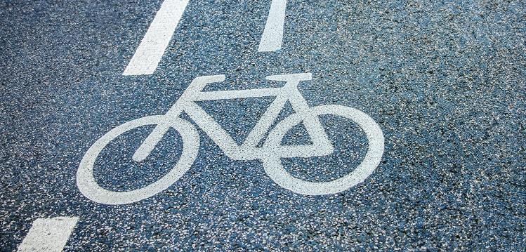 Hvidt cykelsymbol og vejstriber malet på en asfalteret cykelsti, der markerer en cykelrute.
