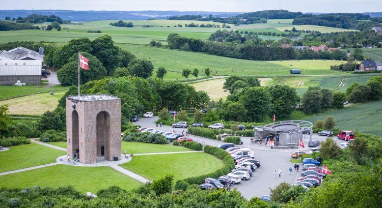 Luftfoto af Ejer Bavnehøj i det østjyske bakkelandskab. I forgrunden ses det karakteristiske tårn med Dannebrog vajende fra toppen. 