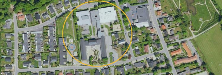 Luftfoto af et område af Låsby med en gul cirkel, der markerer Låsby Skole. 