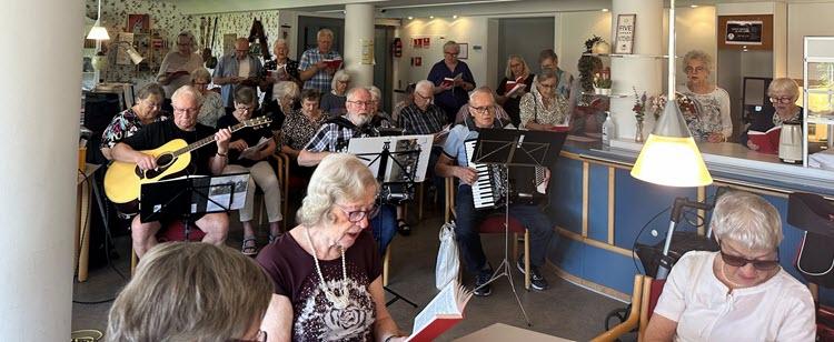 Ældre mennesker med instrumenter og sangbøger synger sammen. 