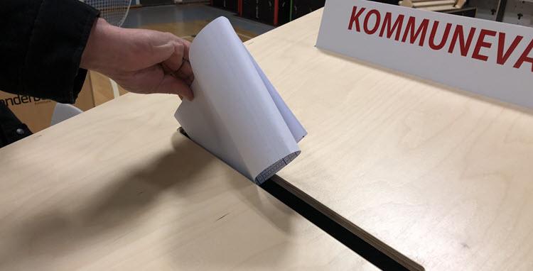 Hånd med stemmeseddel ved valgurne. 