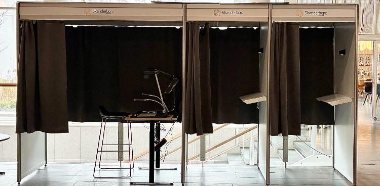 Stemmebokse til brevstemmer på Skanderborg Fælled. Til venstre er en stemmeboks med hjælpemidler og mod højre to almindelige bokse. 