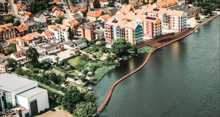 Illustration af Søbroens kommende udseende i fugleperspektiv med Skanderborg by til venstre i billedet og søen til højre. Broen bygges i træ og kommer til at gå fra Bybadet til Lille Nyhavn. Ved Lille Nyhavn opføres en større opholdstrappe.