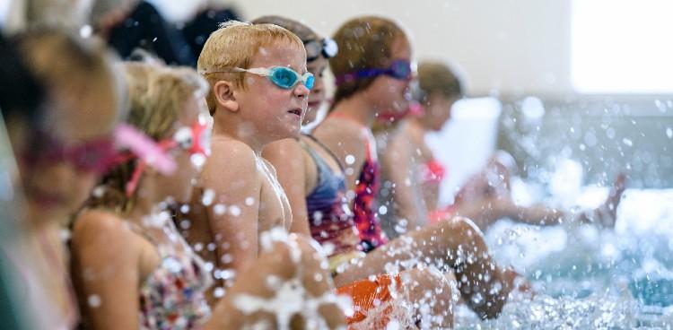 Billedet viser børn i svømmehallen stående på række langs kanten. Dykkerbriller og vandsprøjt.  Foto: Palle Peter Skov