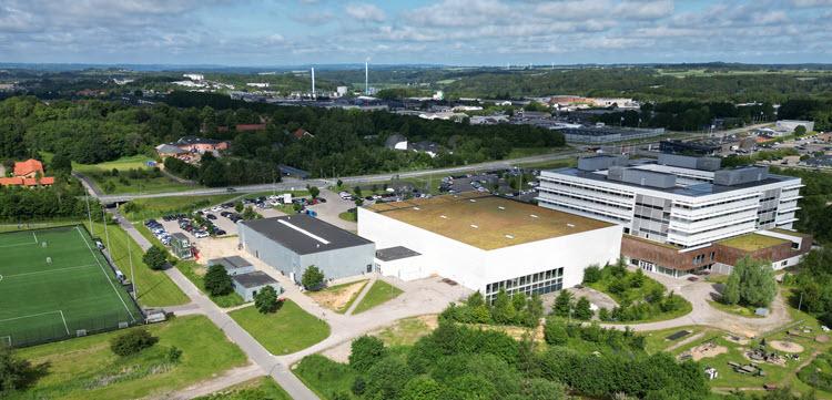 Dronefoto af Skanderborg Fælled grønne træer og fodboldbaner i forgrunden og Skanderborg by i baggrunden.
