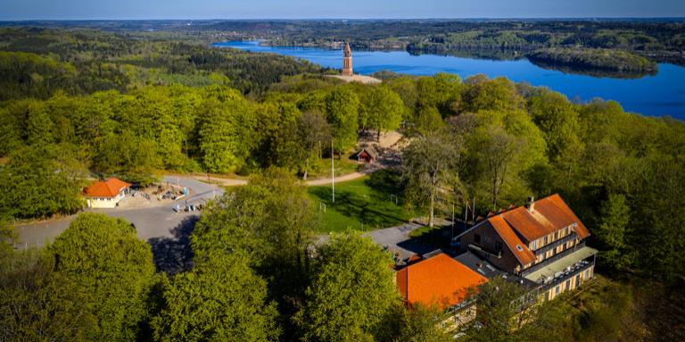 Dronefoto af Himmelbjerget, søen, de grønne træer og Hotel Himmelbjerget i forgrunden. 
